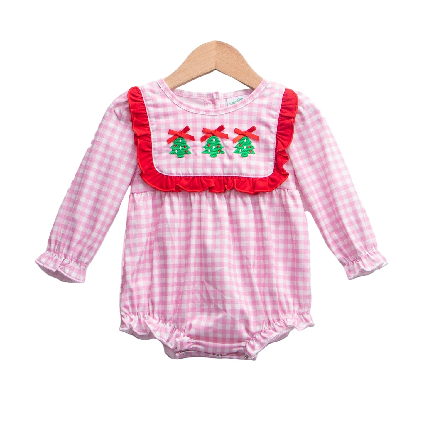 Pink gingham baby girl romper featuring a red ruffle bib with three embroidered Christmas trees and red bows, long sleeves, and bubble hems, hanging on a wooden hanger against a white background.