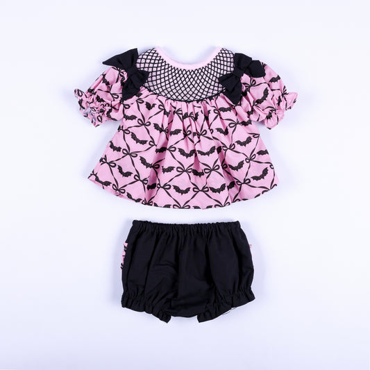 Pink halloween bat print smocked top with black bow accents and matching black bloomers baby girl outfit.