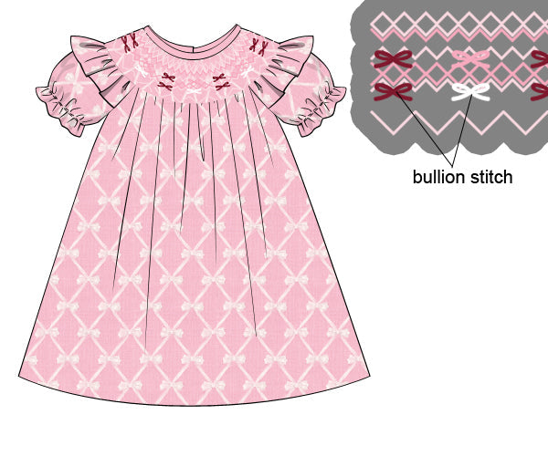 Pink children's dress with bow pattern and bullion stitch details on a white background.