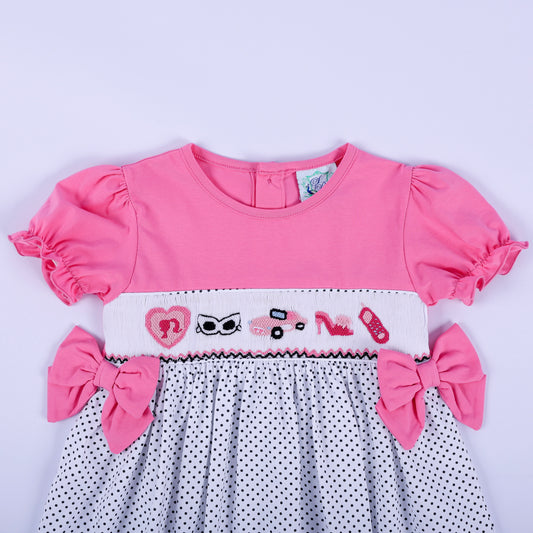 Close-up of hand embroidered fashion motifs on white hand smocked chest plate of girls pink polka dot dress.