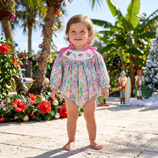 A toddler wears the smocked Christmas bubble romper.