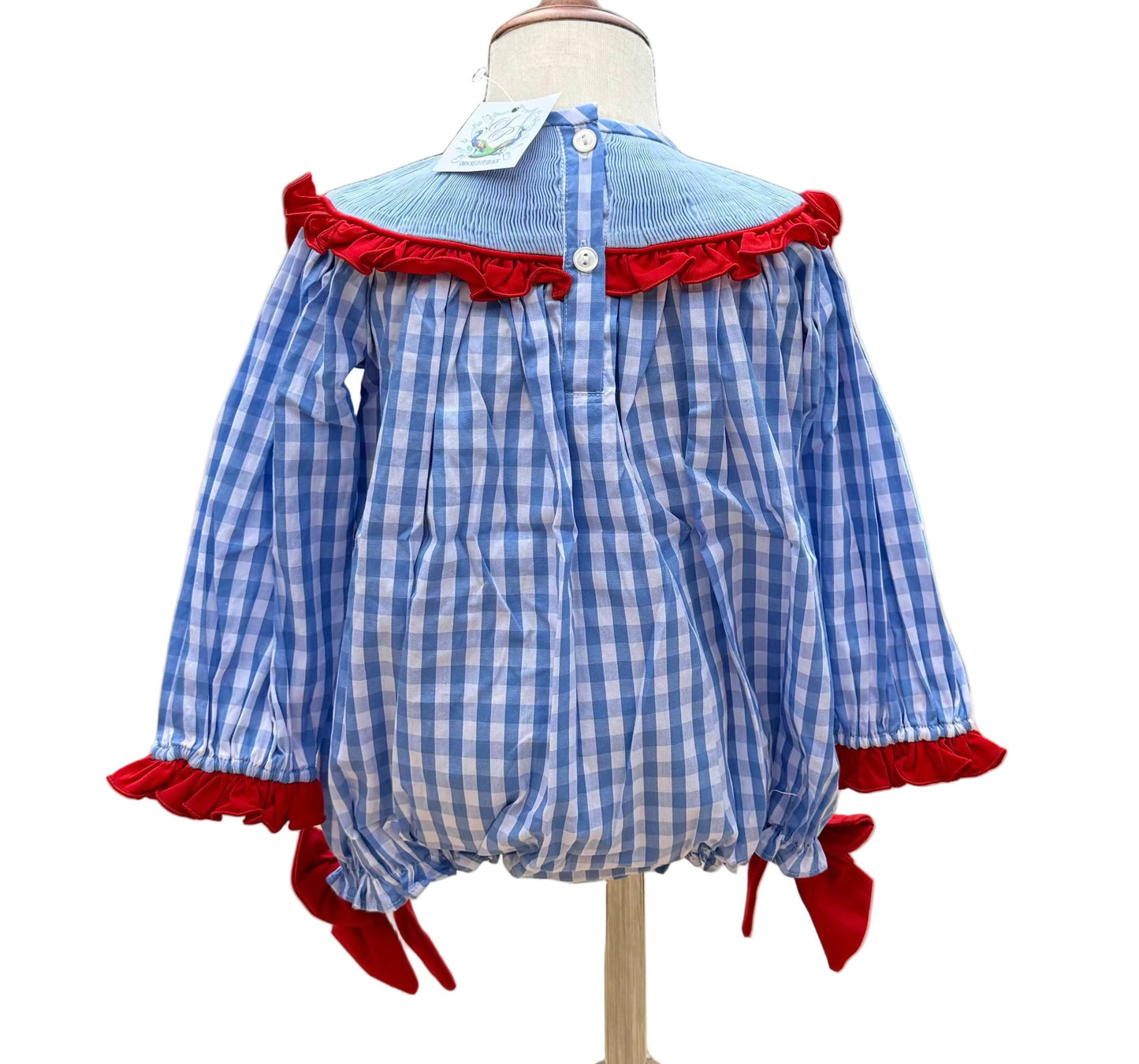 Back view of girls blue gingham hand smocked reindeer bubble with red ruffle trim and buttons.