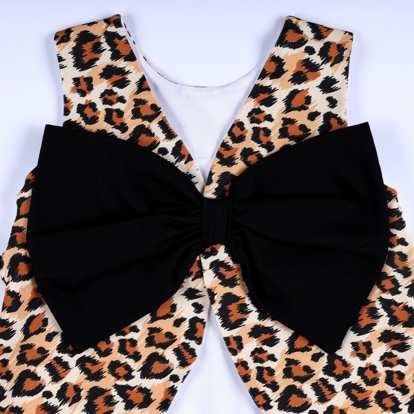 Close-up view of the oversized black statement back bow on the girls leopard print safari smocked top.