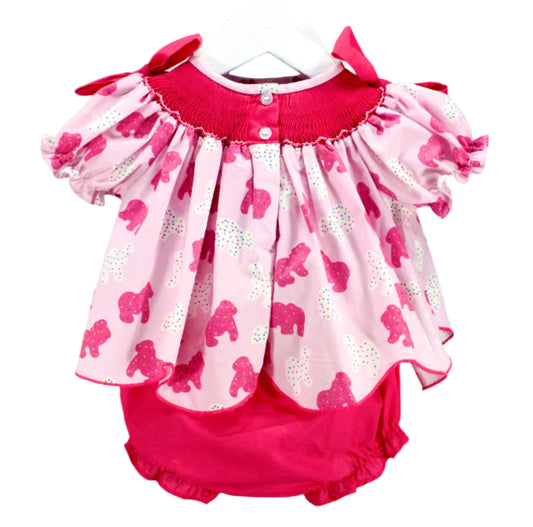 view of hand smocked frosted sprinkle animal cookies set top with button closure detail and pink ruffle bloomers.