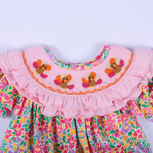 Close-up of the embroidered turkey details on the pink ruffled smocked collar of the floral Thanksgiving baby romper.
