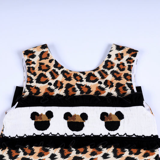 Hand smocked chest panel with embroidered safari mouse ears and black ruffle trim on leopard print top.