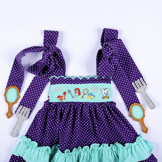 Close-up view of the hand smocked bodice and tied shoulder straps on the purple under the sea bloomer set.