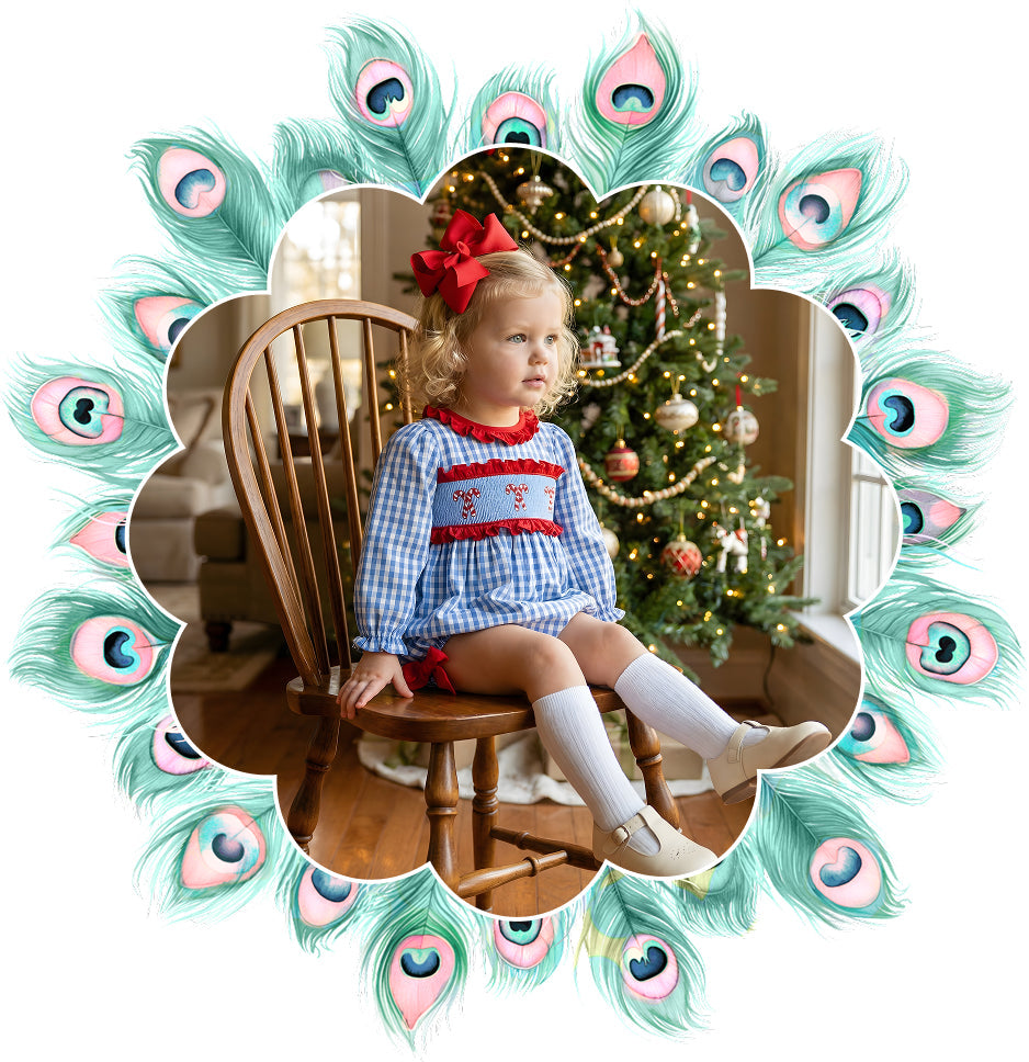Two sisters wearing matching sibling outfits from Smocked Peacock, featuring a navy blue girls smocked Christmas dress and a smocked bubble baby girl outfit.