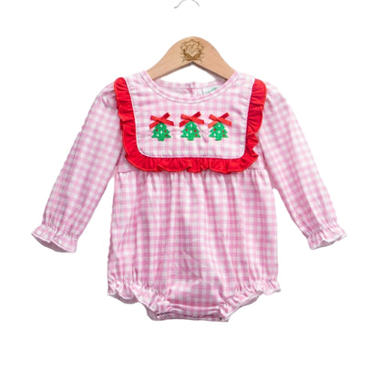 Pink gingham baby girl romper featuring a red ruffle bib with three embroidered Christmas trees and red bows, long sleeves, and bubble hems, hanging on a wooden hanger against a white background.