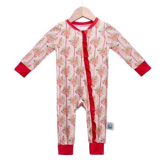 Light pink long-sleeve zippy featuring a festive holiday print with pink bows, holly leaves, and red berries, accented by a red ruffled zipper and matching red cuffs.