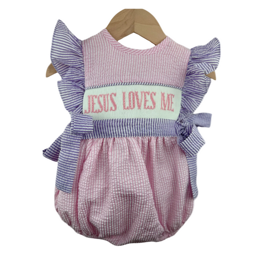 Hand Smocked Girl Bubble featuring pink seersucker fabric, purple striped ruffled sleeves, and "Jesus Loves Me" embroidered across the chest.