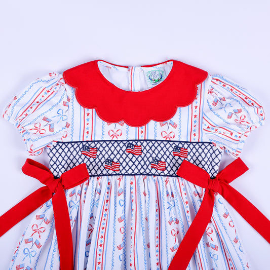 Close-up view of hand smocked American flags on the bodice of the girls red white and blue patriotic party dress.
