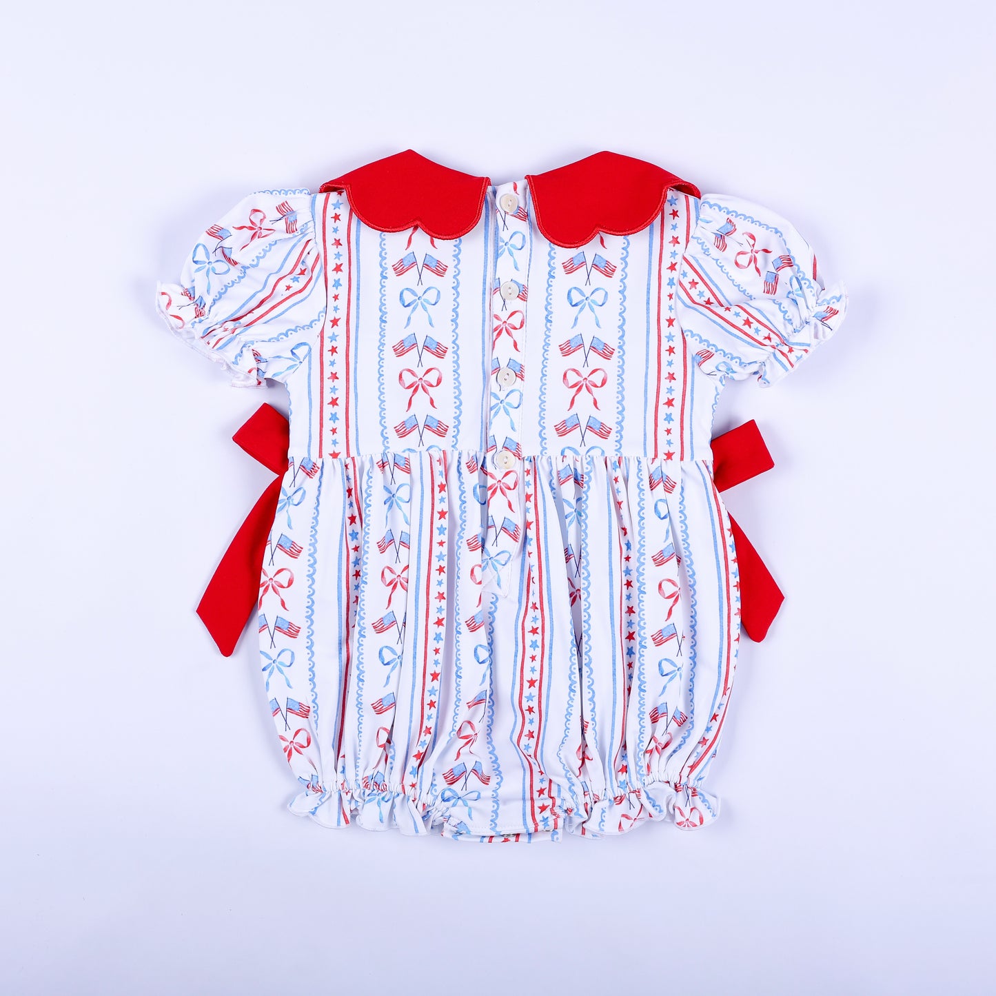 Full back view of America the Beautiful hand smocked baby bubble featuring button-down back closure and red side bows.