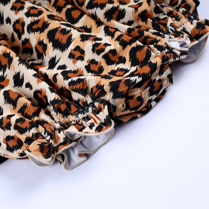 Bottom view of leopard print smocked bubble romper showing snap closures and elastic ruffled leg openings for baby.