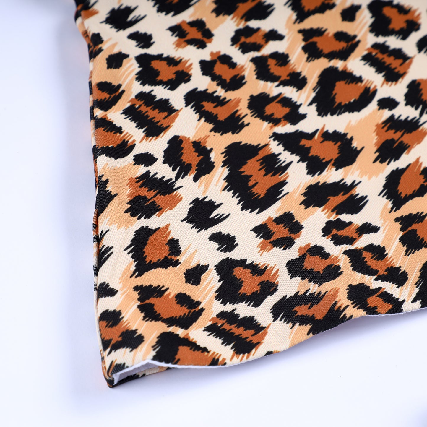 Close-up of premium safari animal kingdom leopard print fabric and hem stitching on smocked top outfit.