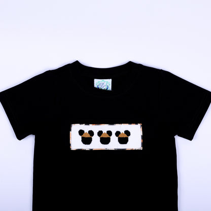 Close-up of boys black crewneck t-shirt featuring hand smocked safari mouse embroidery plate on chest.