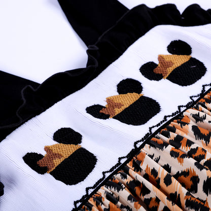 Detailed close up shot of hand embroidered safari mouse heads on white smocked chest panel of leopard dress.