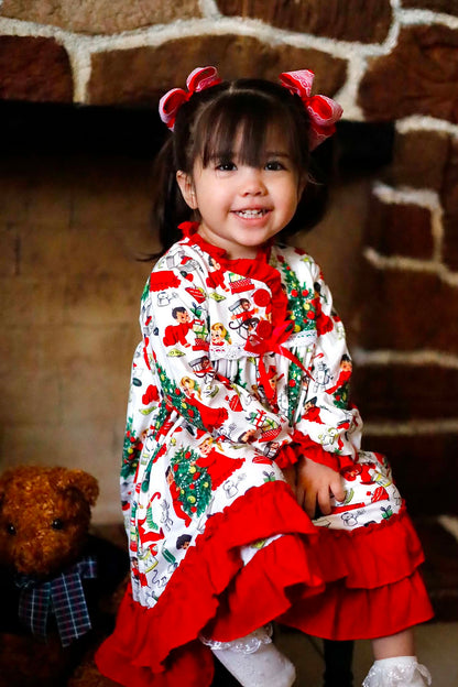 Toddler smiling in Antique Christmas Morning Child's Play Nightgown with red ruffles sitting near a fireplace.