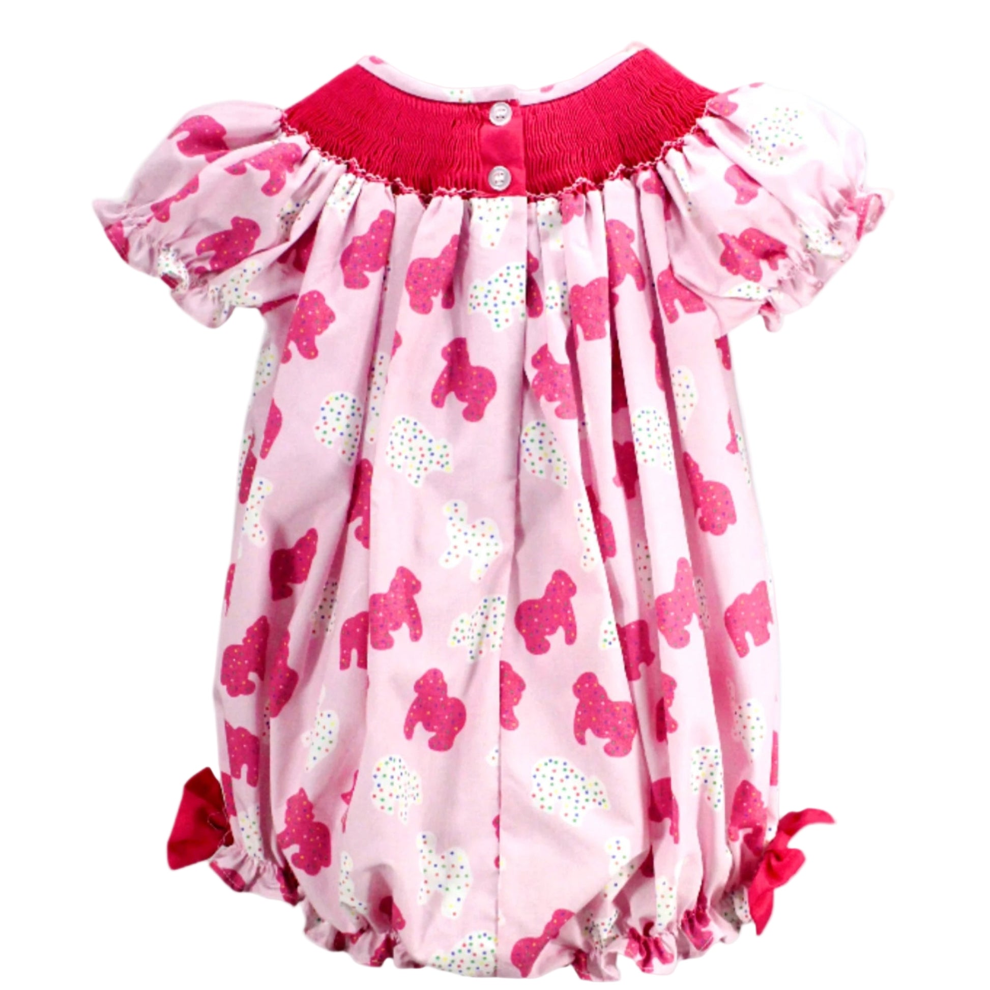 Back view of a baby girl pink bubble romper with a sprinkle elephant print, featuring a fuchsia smocked yoke with top button closures, puff sleeves, and pink side bows.