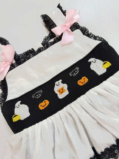 Close-up of hand-smocked black chest panel with embroidered ghosts, pumpkins, and spiders
