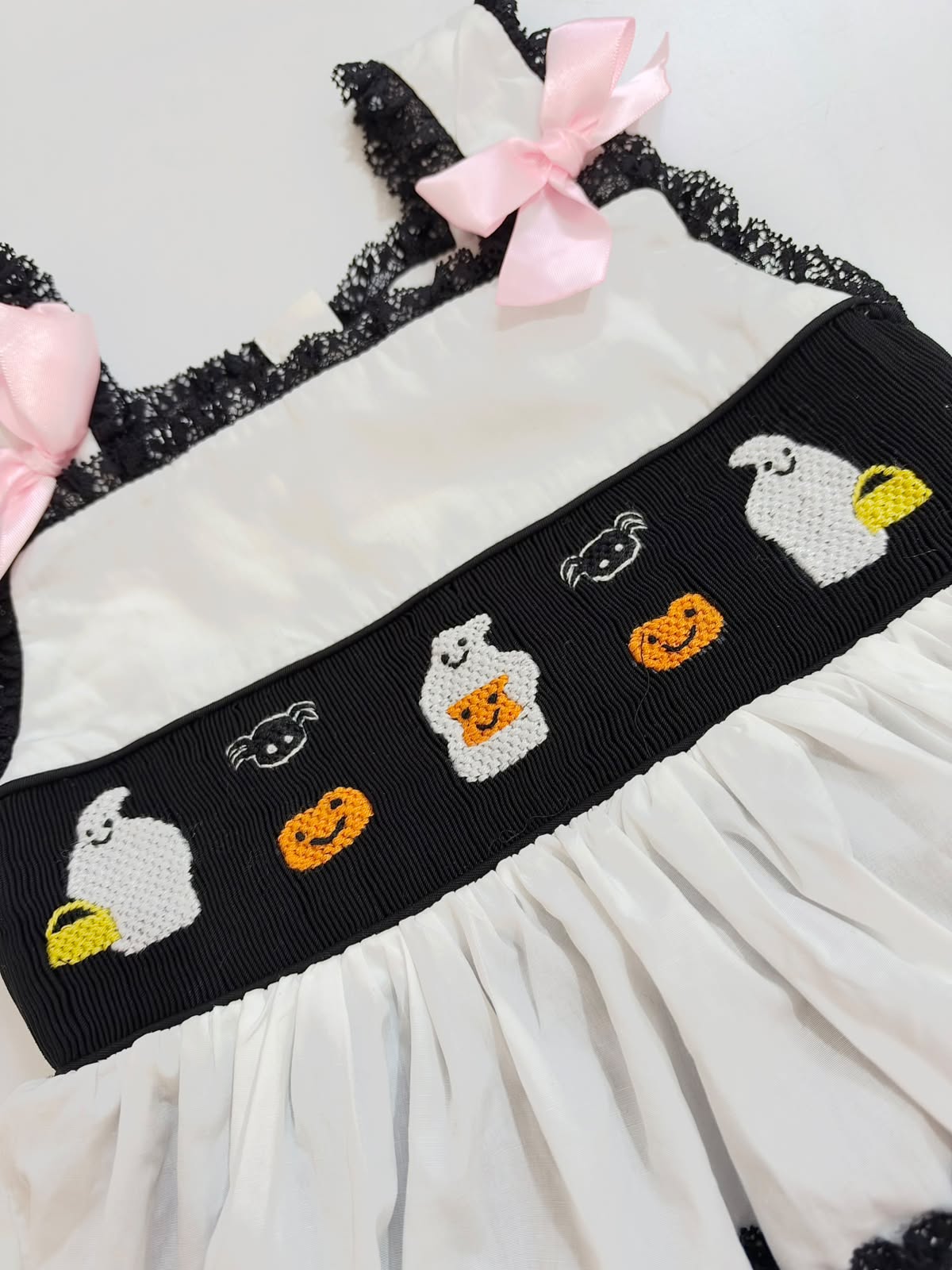 Hand-embroidered Halloween ghosts and pumpkins on smocked chest panel of baby girls romper