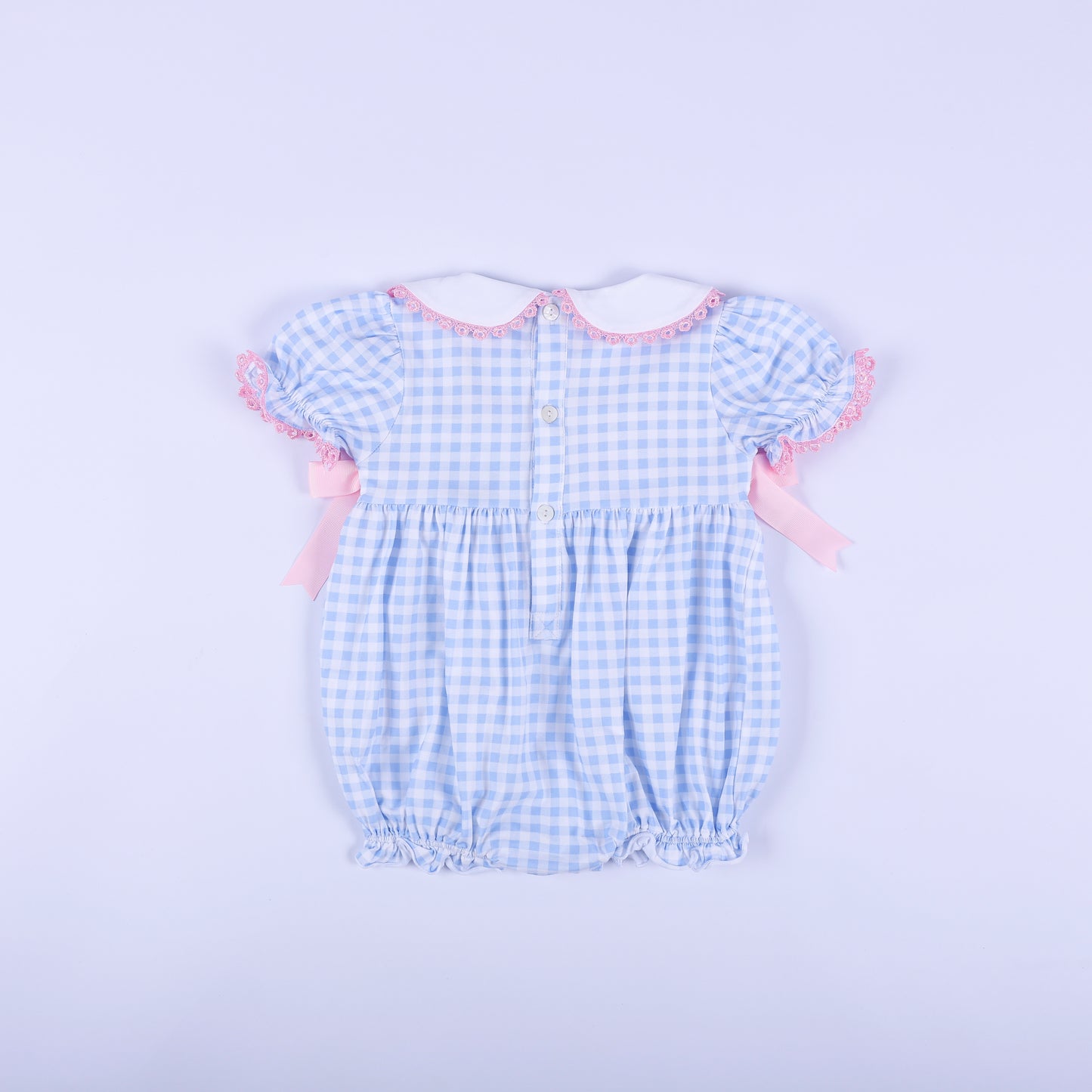 Back view of the blue gingham baby shower gender reveal smocked bubble romper showing functional button closure.