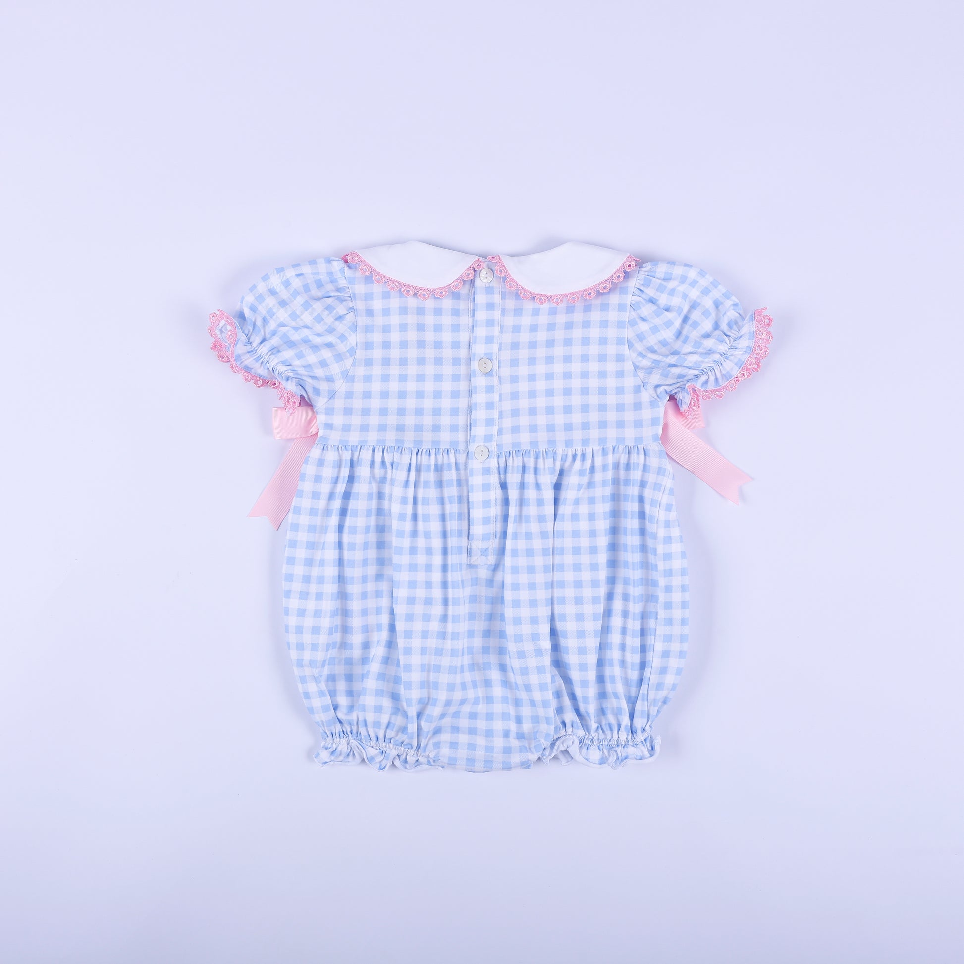 Back view of the blue gingham baby shower gender reveal smocked bubble romper showing functional button closure.