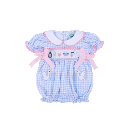Front view of a blue gingham baby shower gender reveal smocked bubble romper with pink bows and embroidered storks.