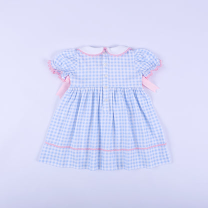 Full back view of light blue gingham gender reveal smocked dress showing white button closures and puffed sleeves.