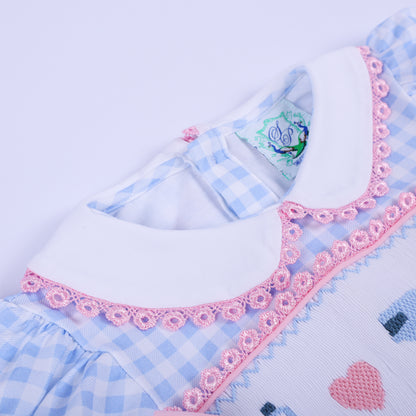 Detailed look at the white Peter Pan collar featuring scalloped pink embroidered trim on blue gingham baby dress.