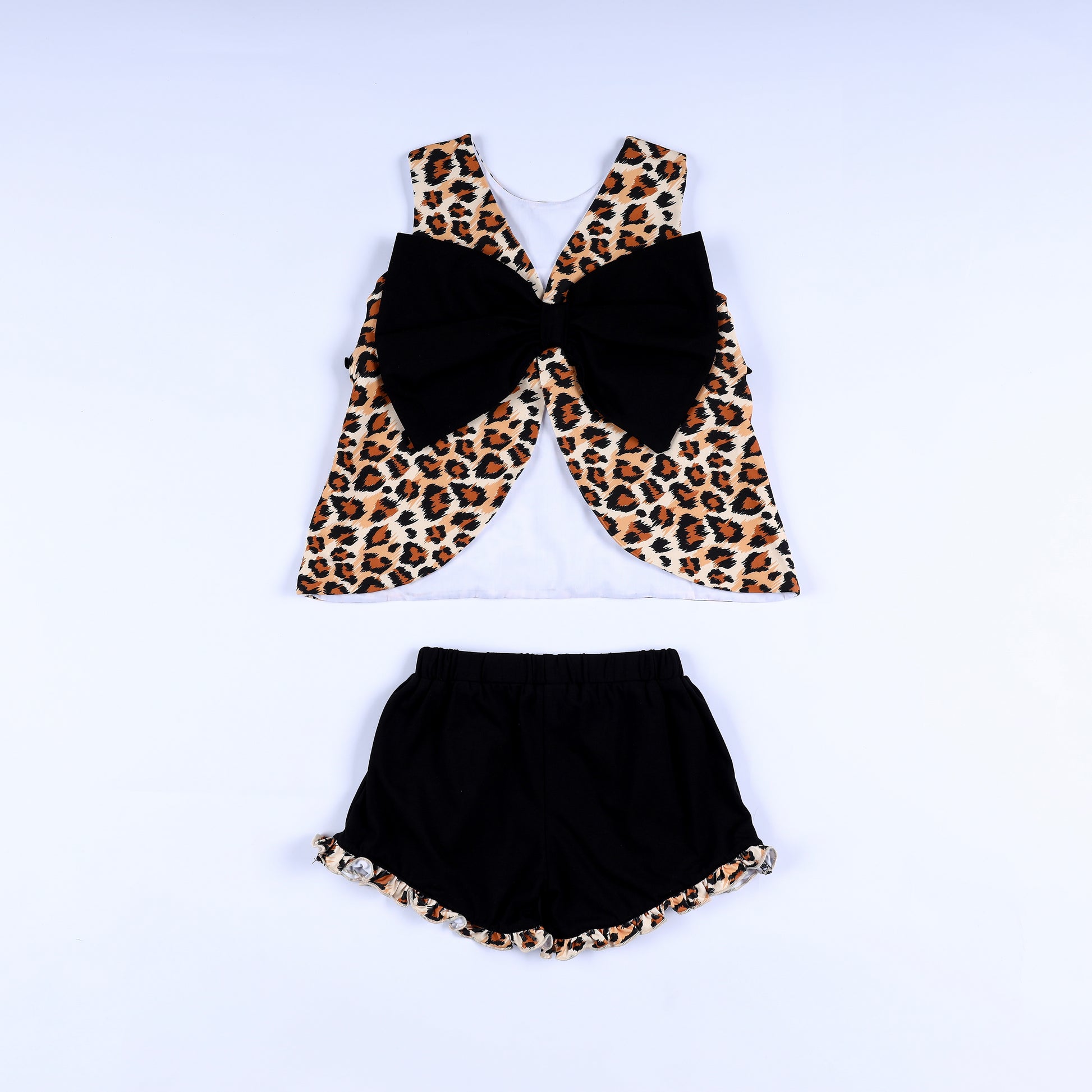 Back view of girls animal kingdom print top with large black bow and matching ruffle hem black shorts.