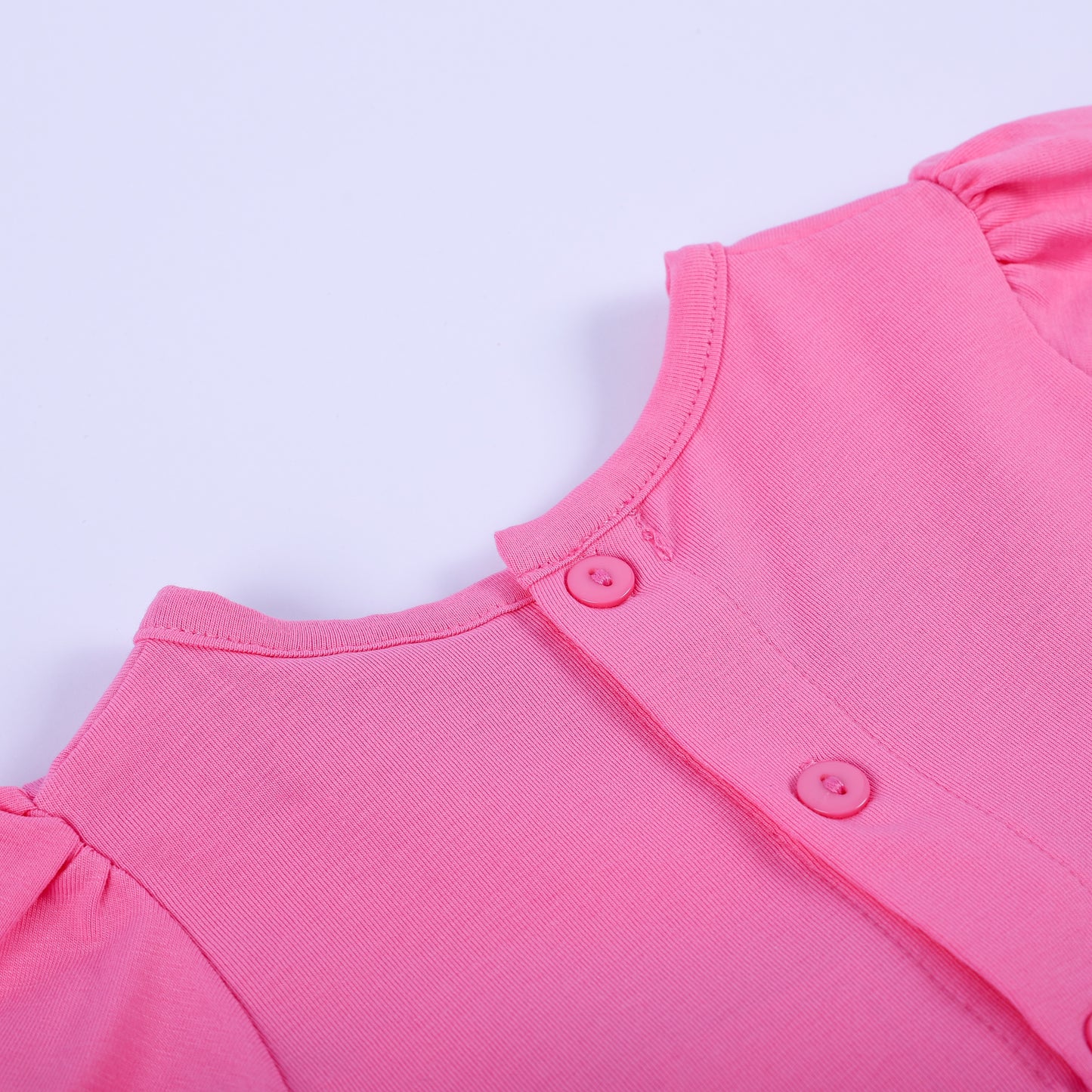 Close-up detail of back button closure and soft pink neckline on hand-smocked fashionista baby girl bubble outfit.