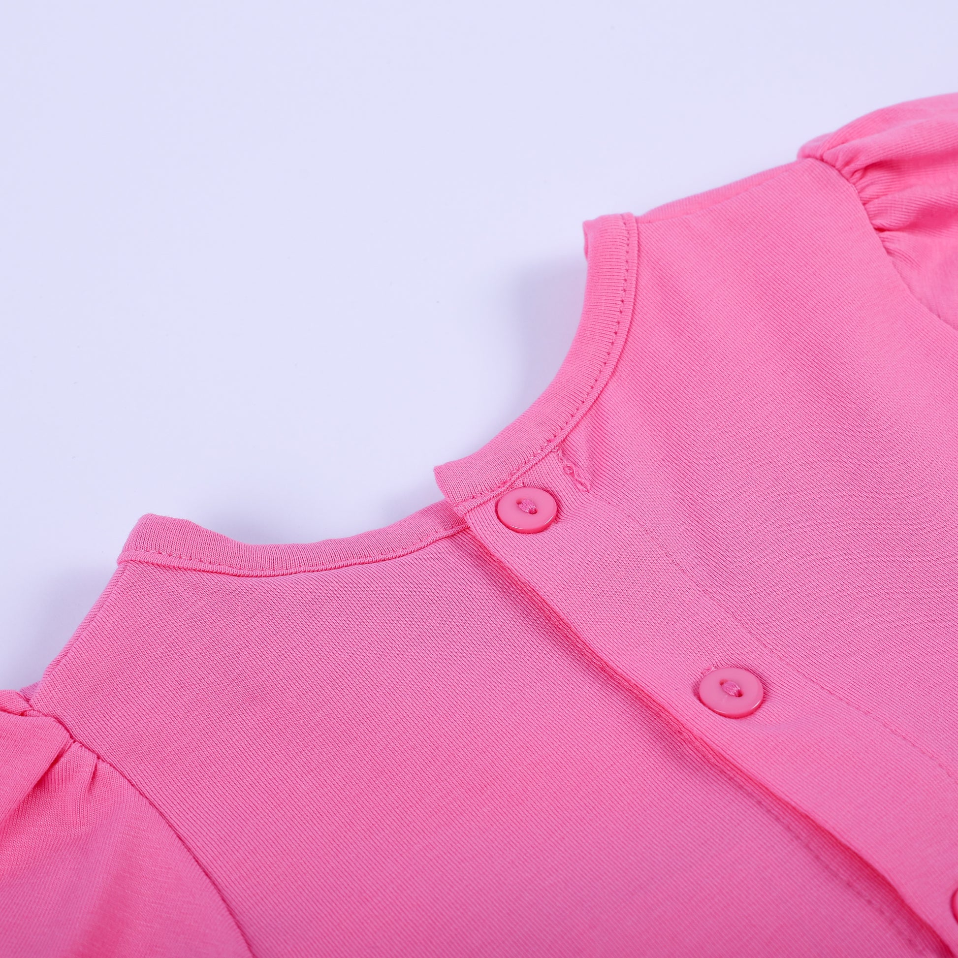 Close-up detail of back button closure and soft pink neckline on hand-smocked fashionista baby girl bubble outfit.