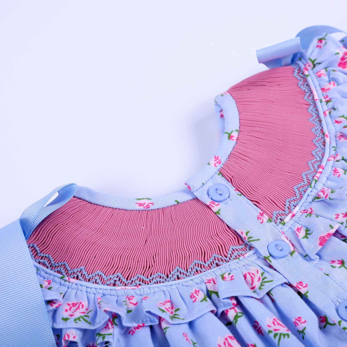 Detail shot of back button closures and pink smocked neck yoke on floral hand-smocked baby girl top.