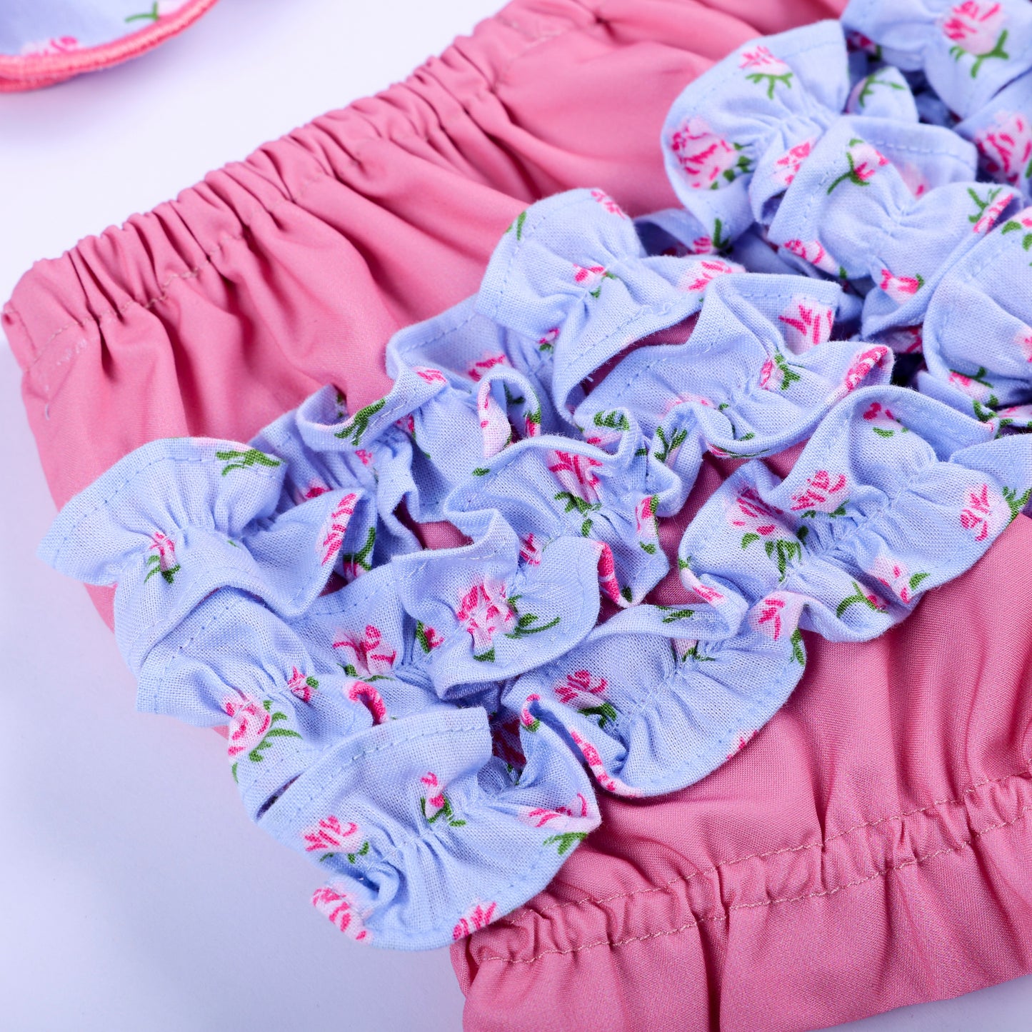 Detailed close-up of layered floral ruffle trim on back of pink diaper cover bloomer set for baby girls.