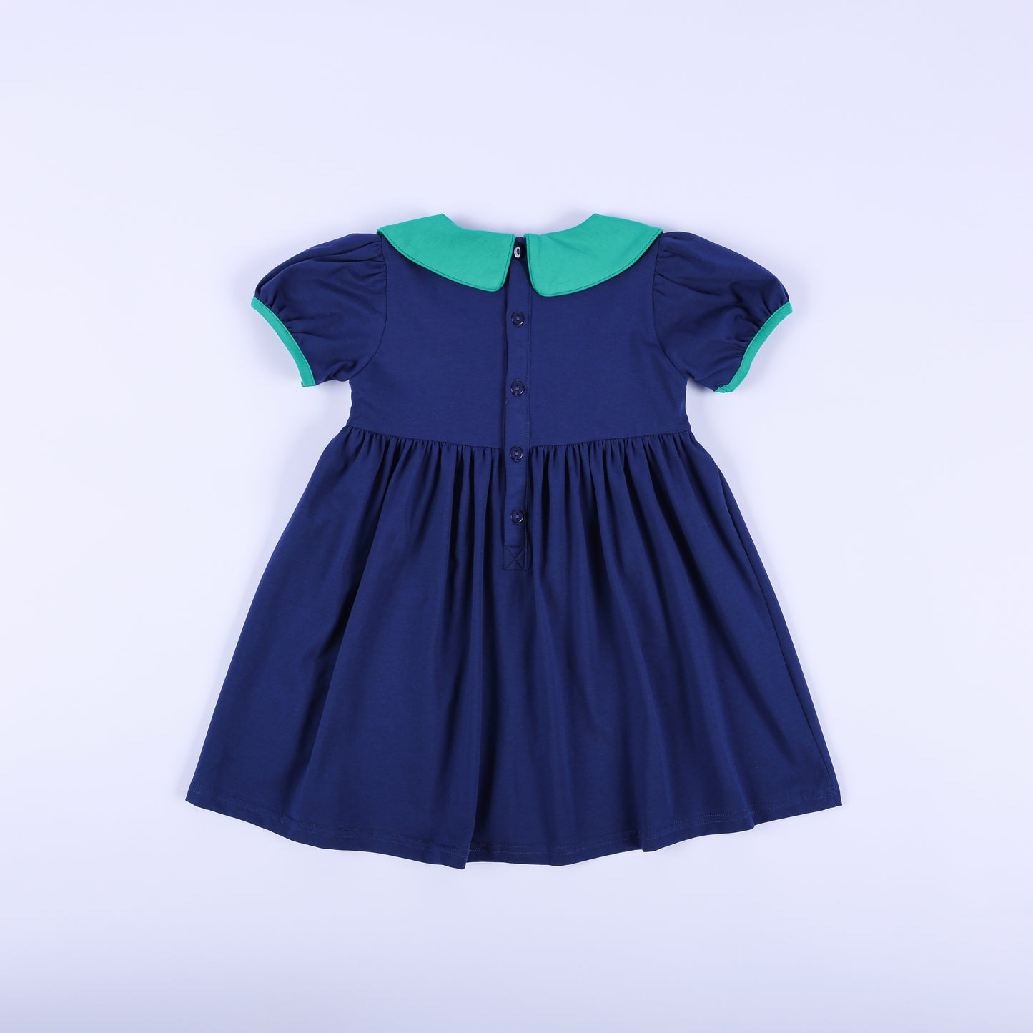 Back view of the 'Jesus Loves the Little Children' navy dress, showing the button-down back closure and solid green collar.