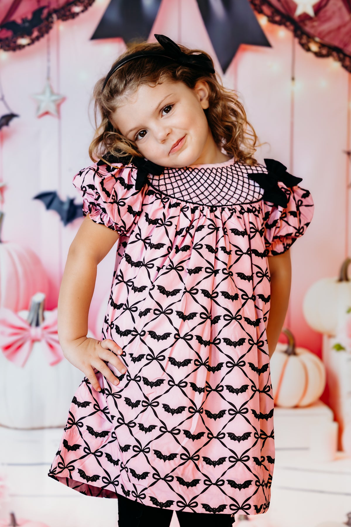 Close-up of girl in Batty for Bows hand smocked dress showcasing black smocking lattice and shoulder ribbon bows.