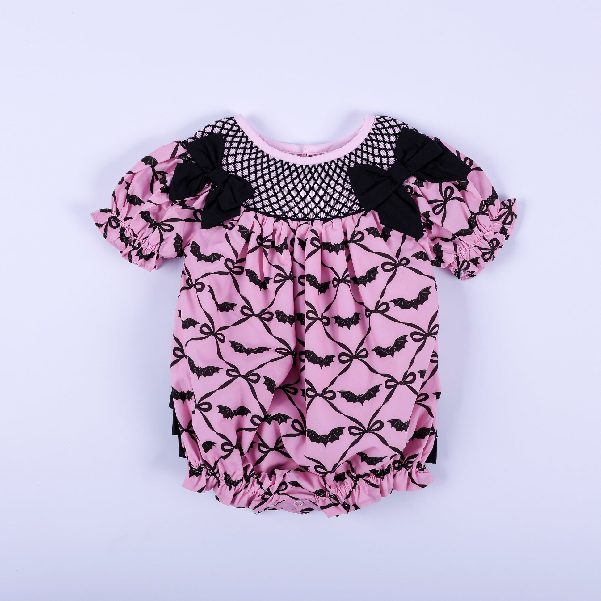 Pink Halloween baby girl hand smocked bubble outfit featuring black bat print and bow accent details.