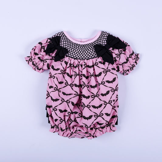 Pink Halloween baby girl hand smocked bubble outfit featuring black bat print and bow accent details.