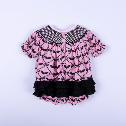 Back view of pink Halloween baby smocked bubble featuring tiered black ruffles and back button closure.