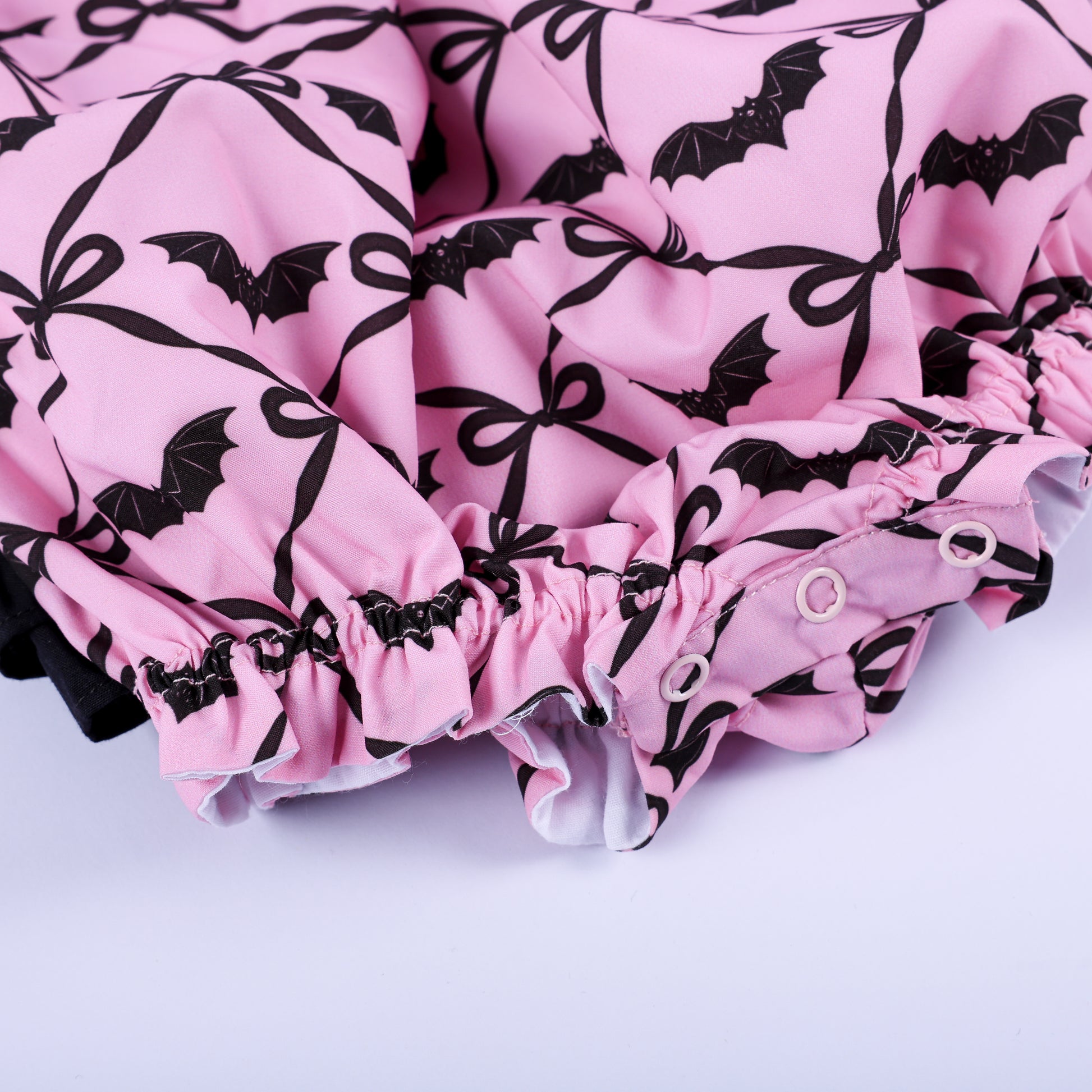 Easy snap closure bottom and elastic leg opening on pink bat print smocked Halloween bubble for infants.