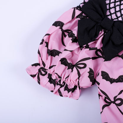Detailed view of puffed sleeve on pink bat print baby bubble with elastic ruffled hem and black accent bow.