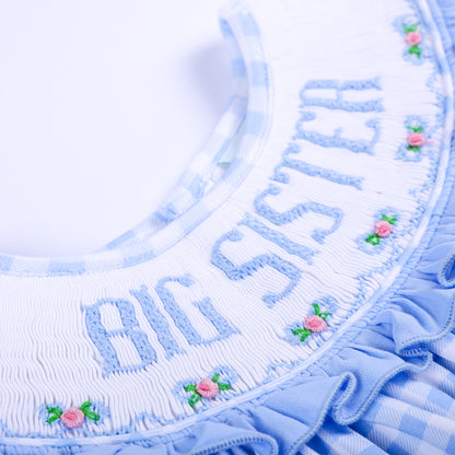 Detailed view of hand-smocked Big Sister embroidered lettering and embroidered flowers on white collar.