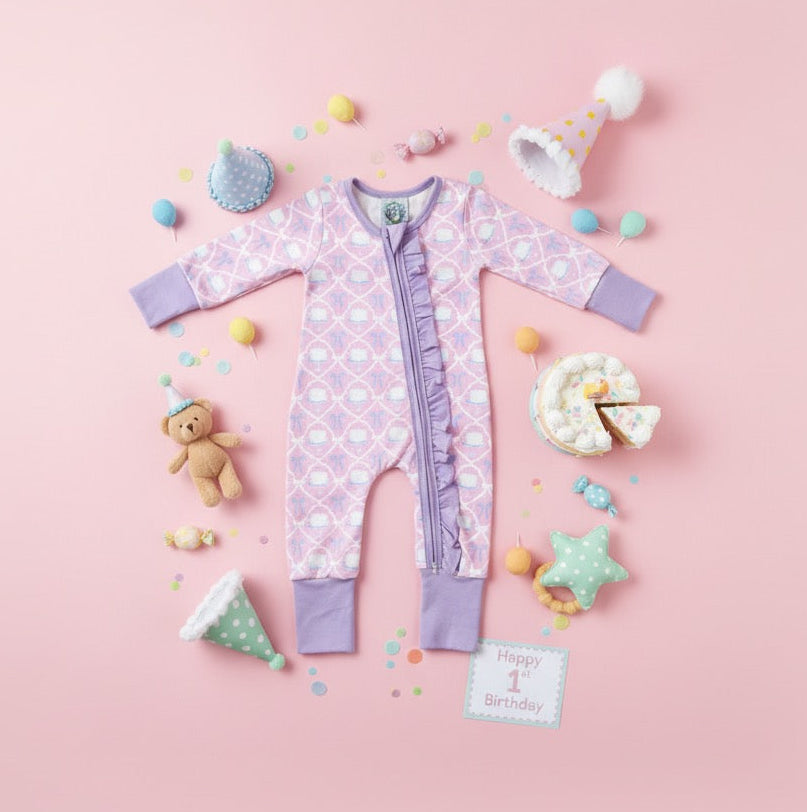 Flat lay of the Birthday Cake and Bow Girl Zippy styled with party hats, a teddy bear, and birthday decor.