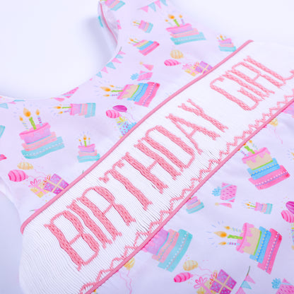 Detailed angle of hand embroidered Birthday Girl lettering on a smocked chest panel for baby clothing.