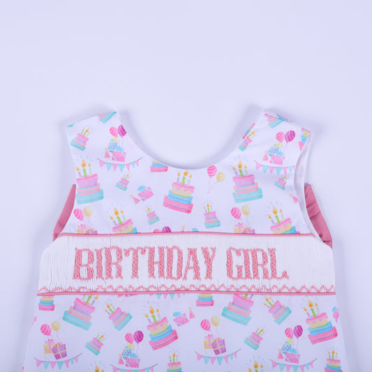 Close-up of the birthday girl hand smocked top bodice showing pink embroidered lettering and pastel birthday cakes.