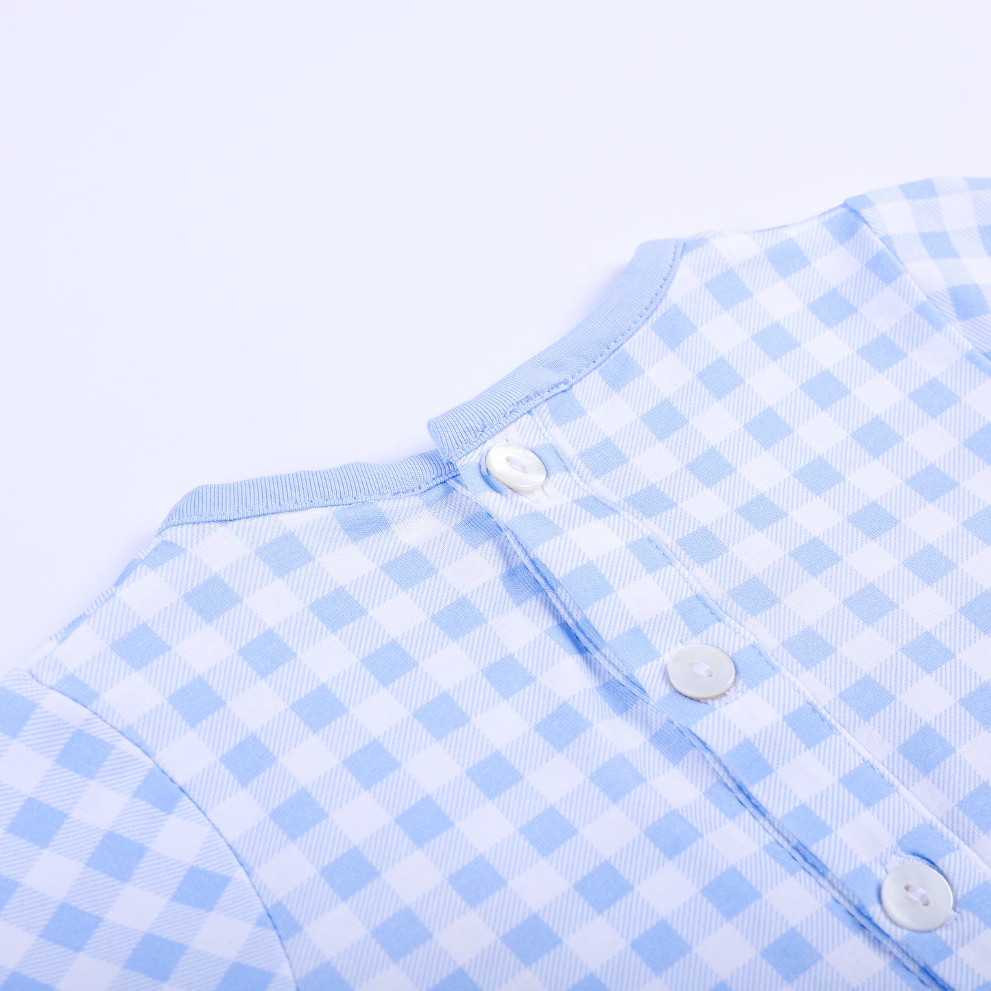 Close up detail of upper back button closures on light blue gingham hand smocked baby boy sleep sack gown.