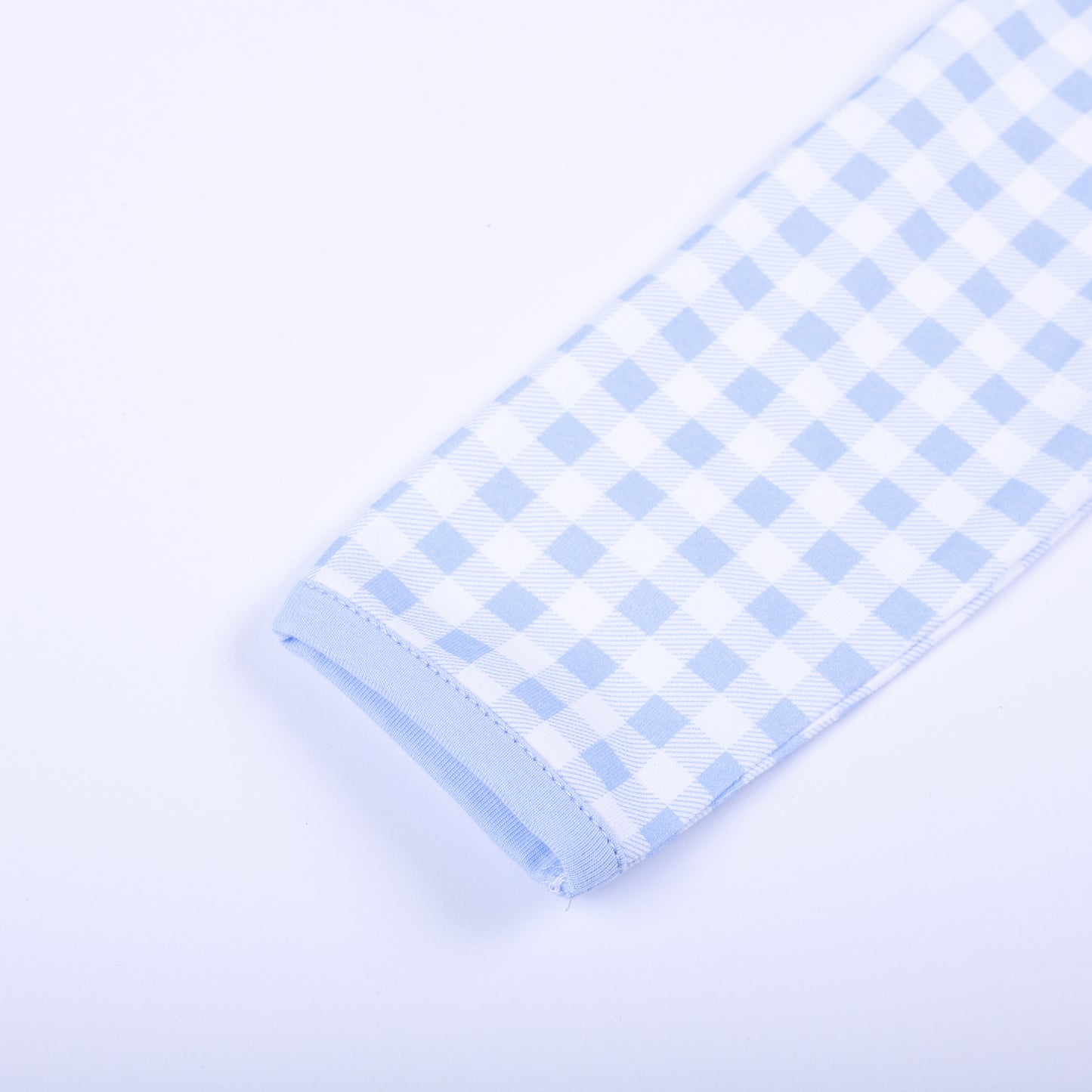 Detailed view of soft long sleeve cuff and light blue trim on baby gingham hand smocked sleep sack layette.