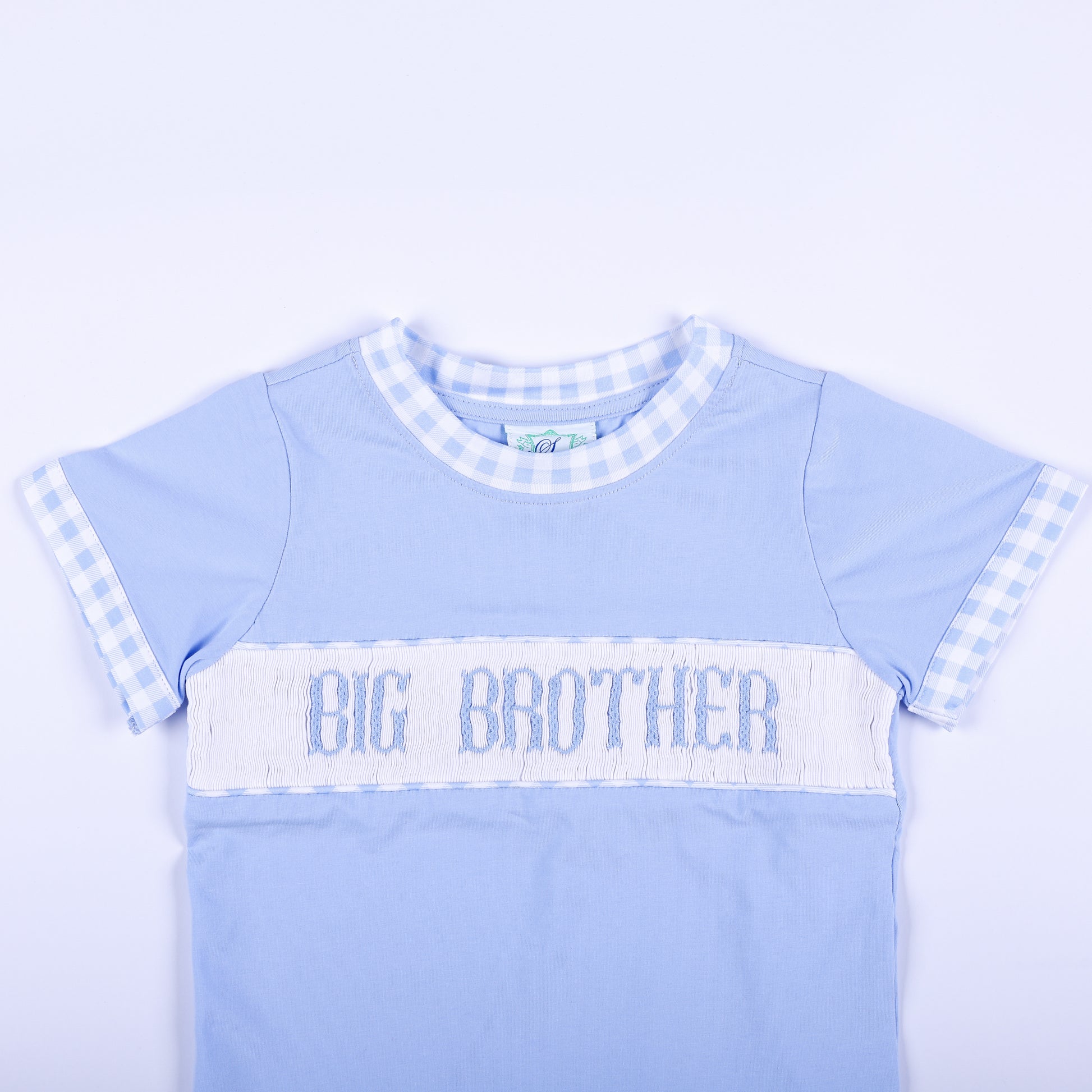 Close-up of light blue shirt featuring hand smocked Big Brother embroidered text panel and gingham collar trim.