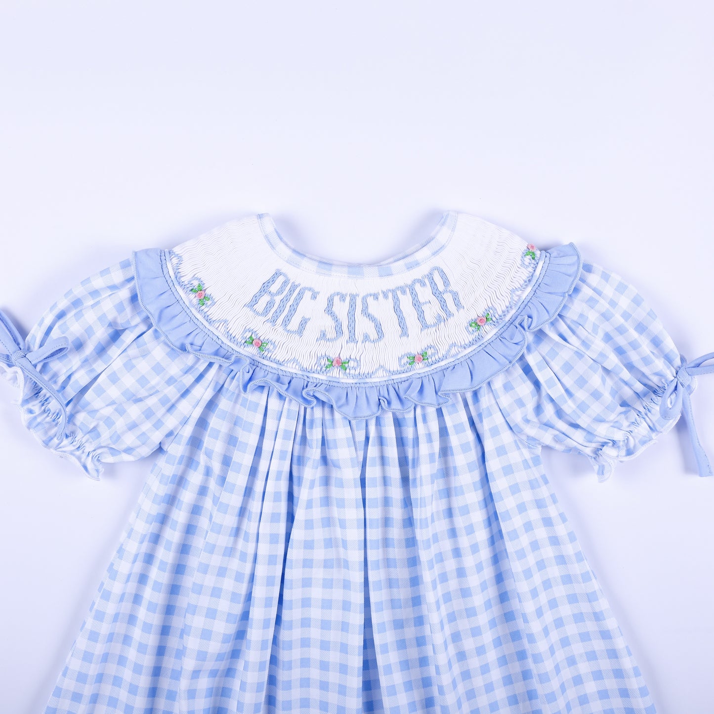 Close-up view of the hand-smocked neckline with Big Sister embroidery on a light blue gingham dress.